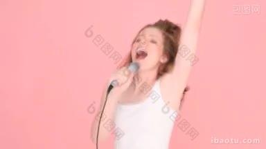 女人唱歌或说话对麦克风上半身工作室肖像上的粉红色与copyspace